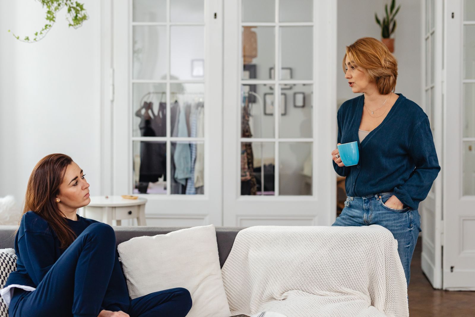 Two sisters having a close conversation on a couch at home