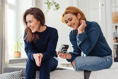 Women Sitting on Gray Surface Smiling Together