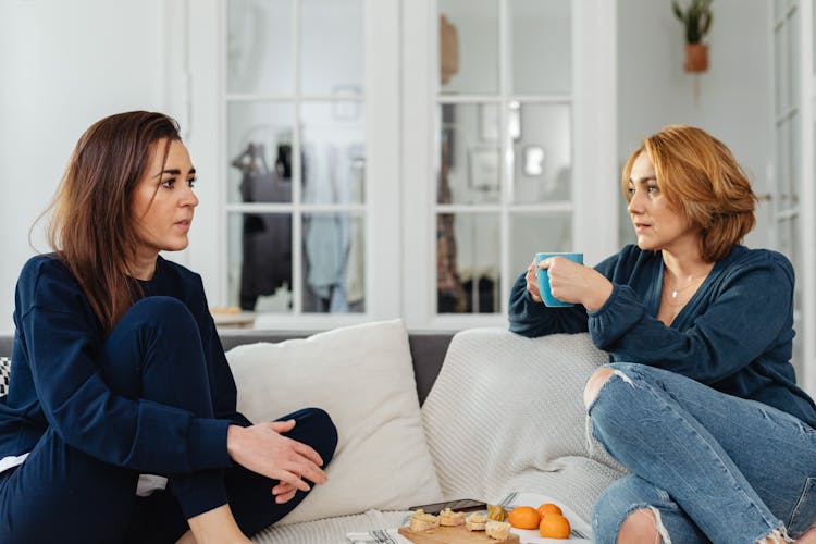 Women Sitting On Couch Drinking Tea