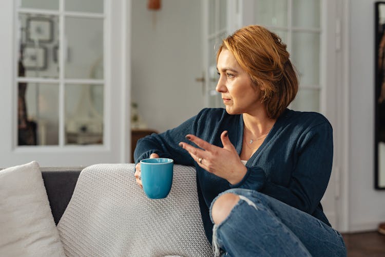 Woman Sitting On Couch With Cup Of Coffee