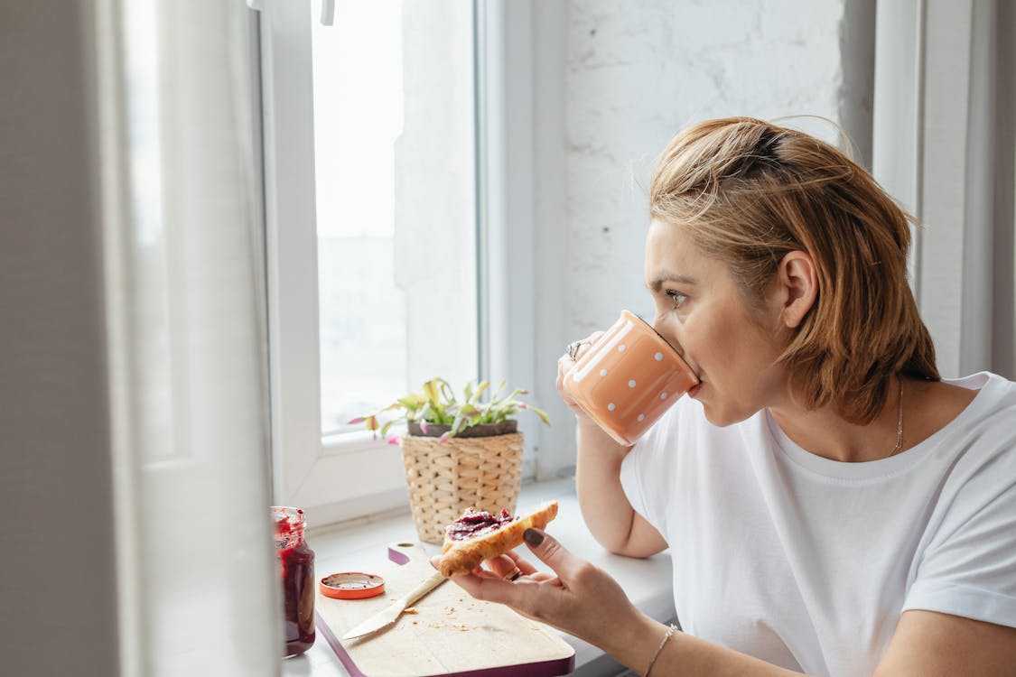 Woman Drinking Coffee on a Peach Colored Mug