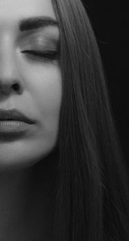 Elegant black and white close-up of a woman's face with closed eyes, capturing serenity.