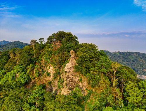 Free Picturesque scenery of huge rocky mountain covered with lush green trees in wild valley against blue sky Stock Photo