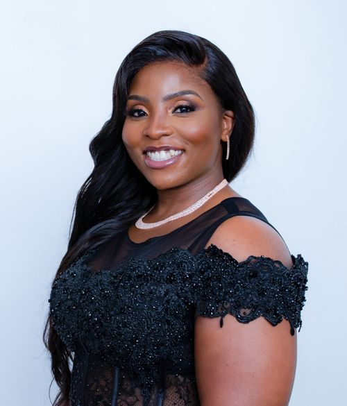 Free A portrait of a confident young woman smiling in a glamorous black dress against a light background. Stock Photo
