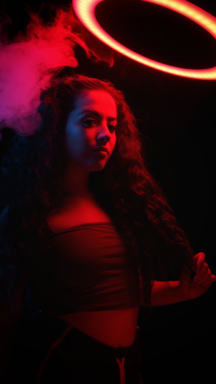 Woman In Dark Neon Room Near Light Ring And Smoke