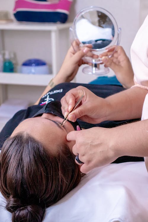Photo of a Woman Lying while Getting Her Eyebrows Plucked