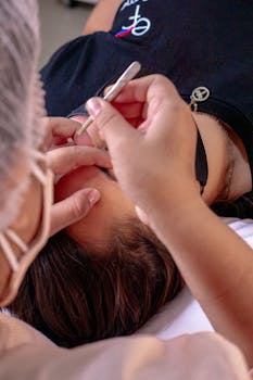 A woman receives precise eyebrow grooming at a spa, showcasing beauty care.