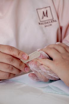 Close-up of a manicurist filing nails in a salon setting, highlighting attention to detail.