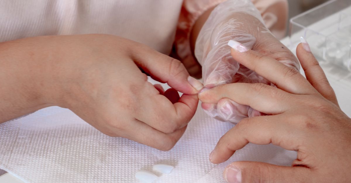 Detailed view of acrylic nail application in a beauty salon, showcasing professional manicure techniques.