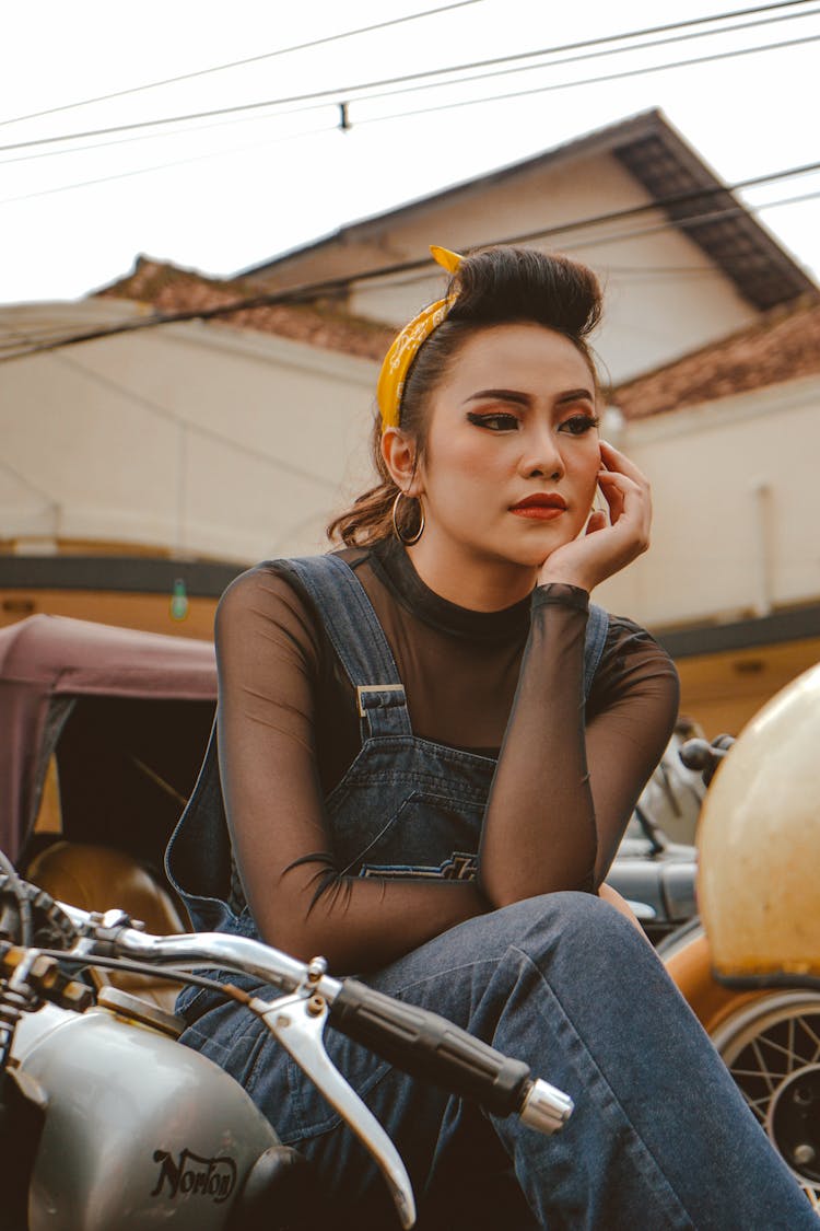 Dreamy Asian Motorcyclist Touching Face On Motorbike In City