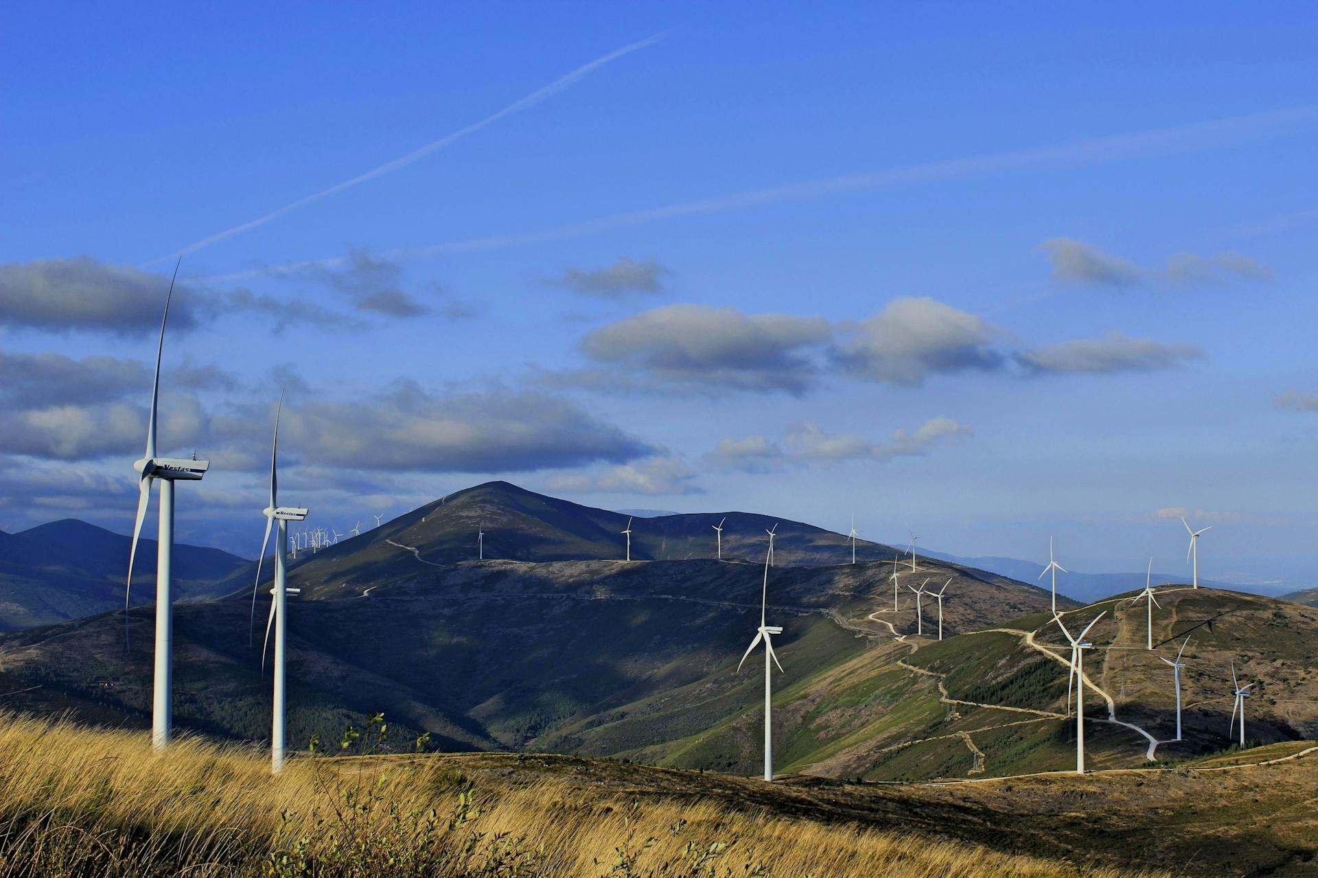 Vast wind farm with turbines in scenic rolling hills under a clear sky, showcasing sustainable energy.