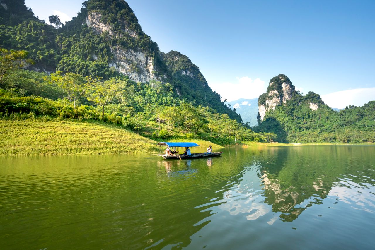 anonymous travelers in boat with canopy sailing on rippled river again