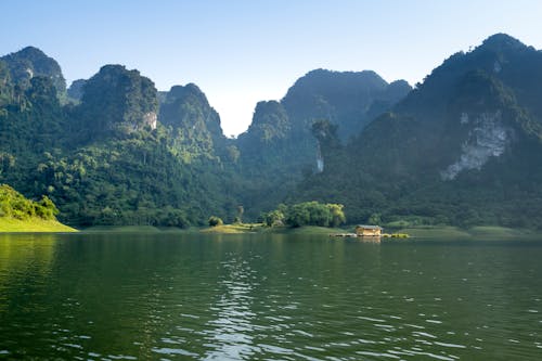 Majestic mountains against river and house in countryside