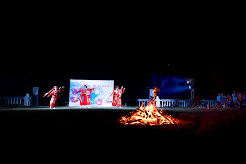 Anonymous ladies on traditional red dresses dancing on stage during Vietnamese fire festival of Pa Then ethnic people in Lam Binh Tuyen Commune at night