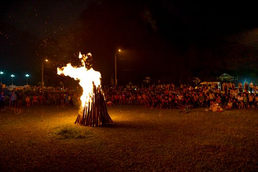 Crowd of unrecognizable people gathered around burning fire against dark night sky during traditional Ha Giang fire festival in Vietnam