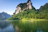 Rocky mountain ridge covered with lush green vegetation near calm lake