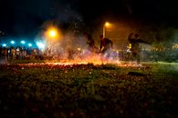 Men in casual clothes running on hot burning coals placed on grass during night show