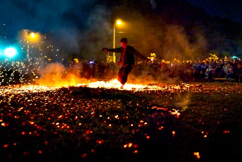 Full body of unrecognizable male running on hot burning coals during show in evening time