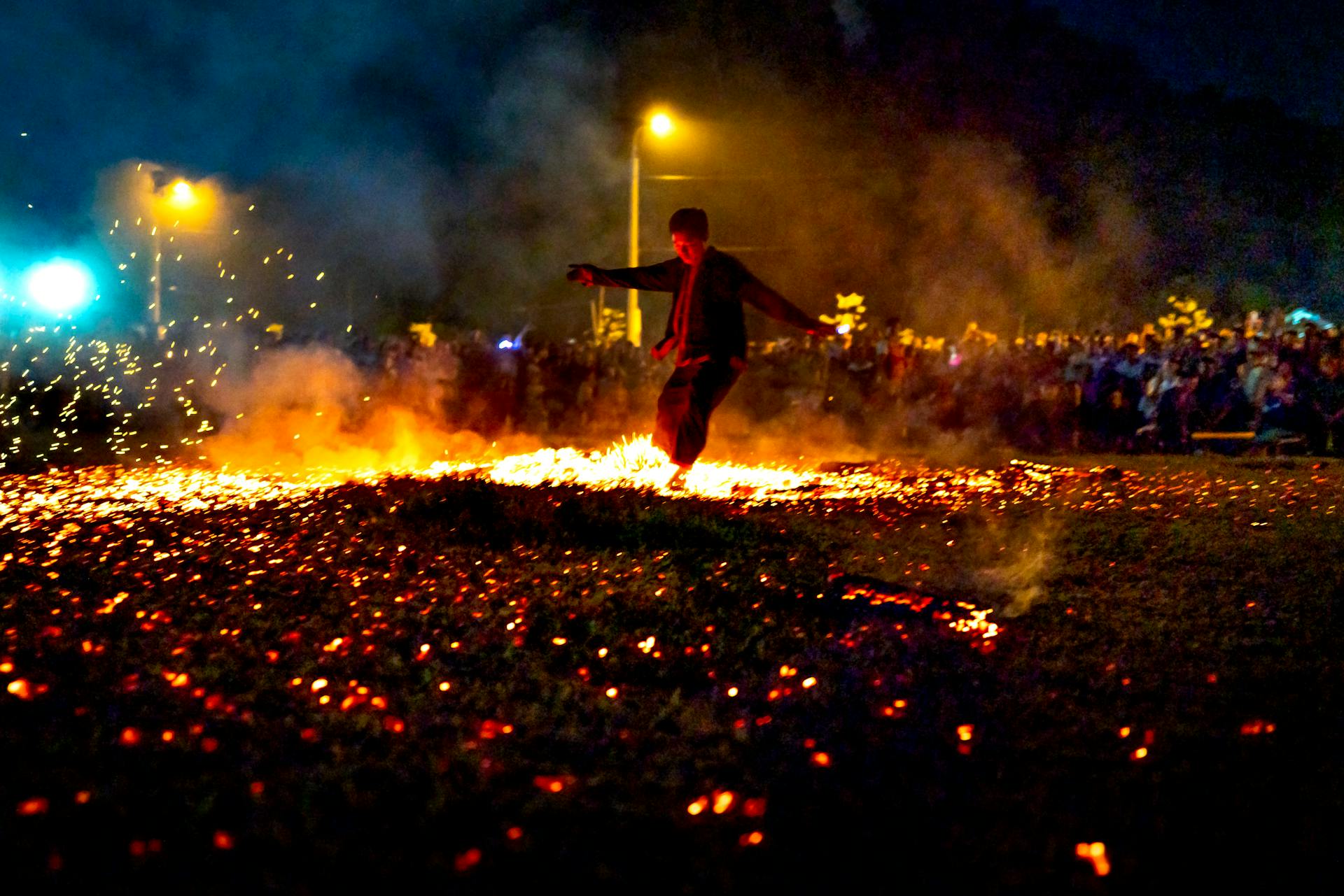 Het hele lichaam van een onherkenbare man loopt op hete brandende kolen tijdens de show in de avond