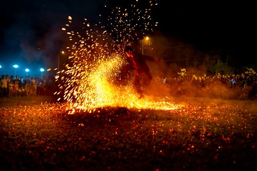 Free Full body of male dancer performing dangerous movement with fire sparks at night among people Stock Photo