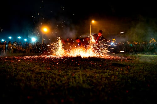 Group of fearless male dancers performing in sparkling bright lights of fire among crowd of people