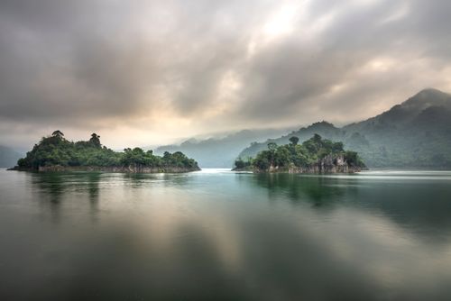 Free Rocky islands under tropical woods in pond surrounded by misty hills in cloudy day Stock Photo