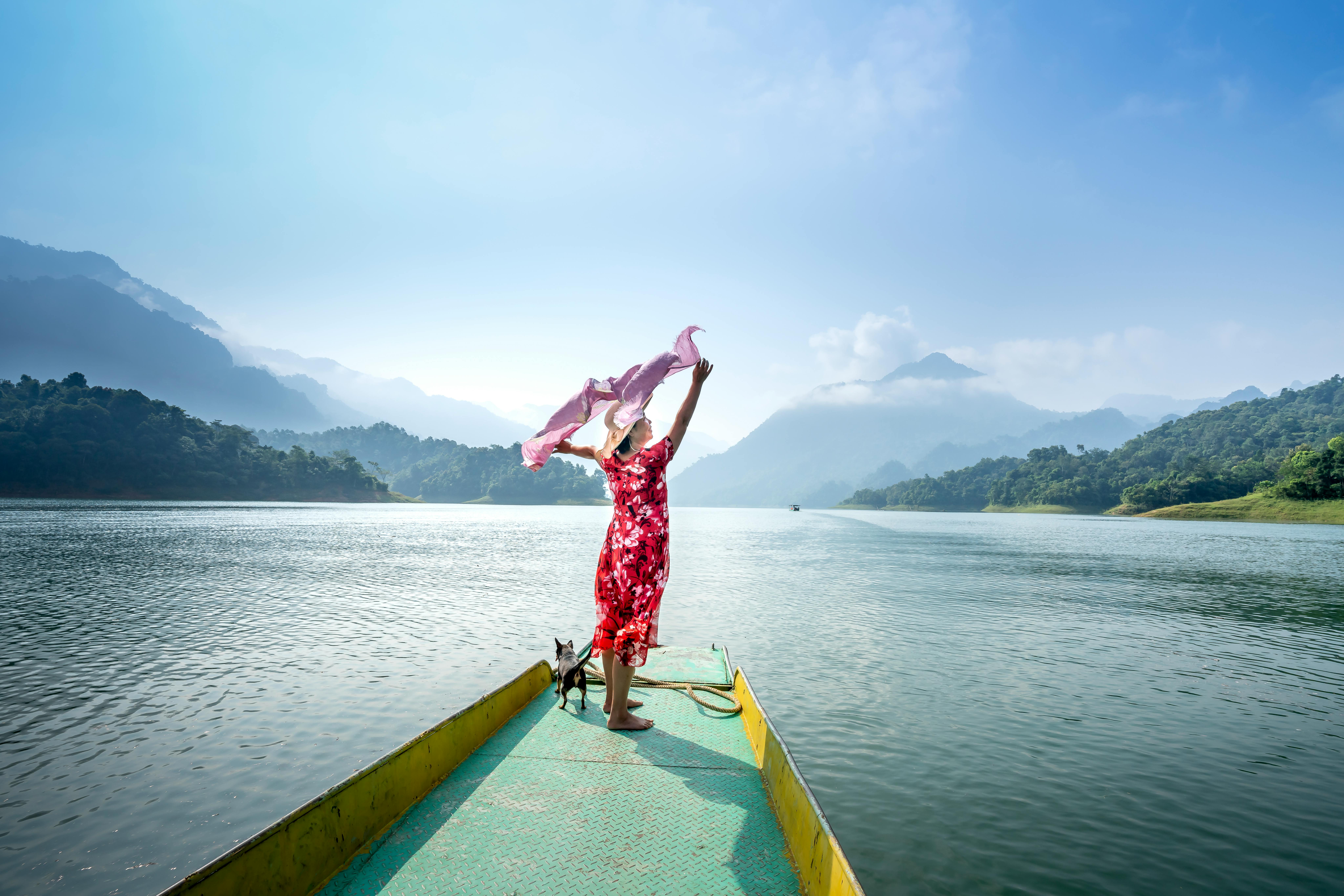 Woman with pet enjoying vacation in lake in hilly terrain
