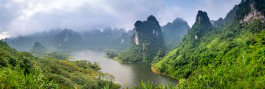 Foggy mountains and river under cloudy sky