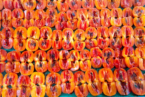 From above of halves of fresh ripe sliced persimmons placed in rows in daytime