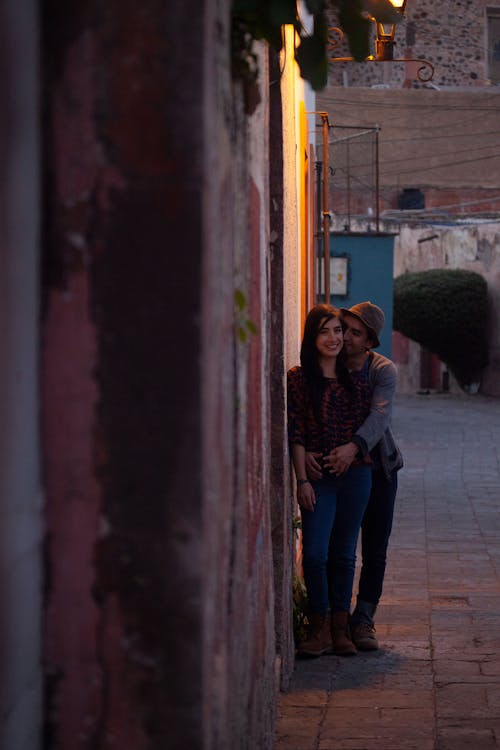 Photo of a Man Hugging a Woman Near a Wall