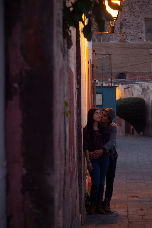 Free Photo of a Man Kissing a Woman Near a Wall Stock Photo
