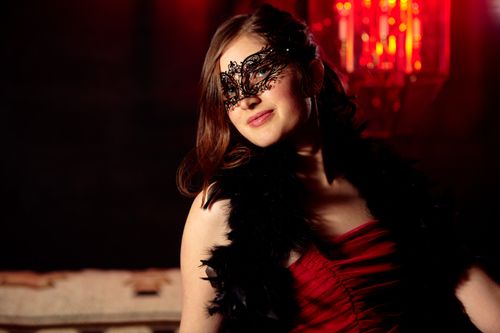 Free Glamorous woman in a masquerade mask at a mysterious night event with red lighting. Stock Photo