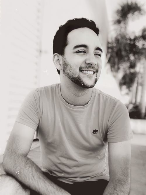 Free A cheerful young man with facial hair smiling in an outdoor black and white portrait. Stock Photo