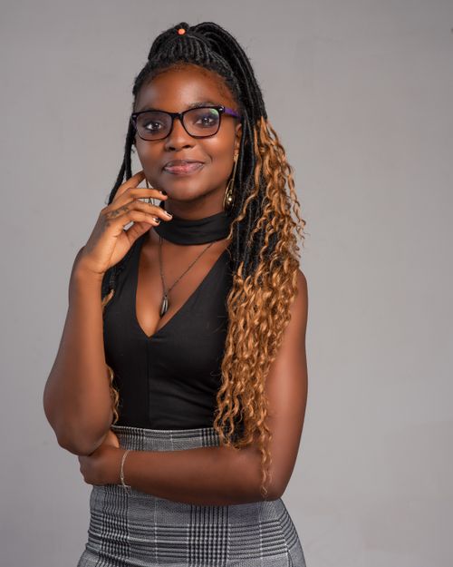 Free Portrait of an elegant young woman with braided hair and eyeglasses, exuding confidence against a gray background. Stock Photo