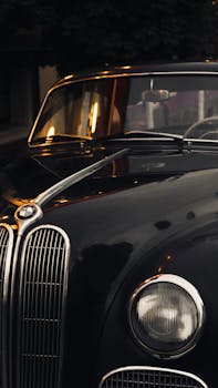 Close-up of a vintage black car with chrome accents, parked outdoors at twilight.