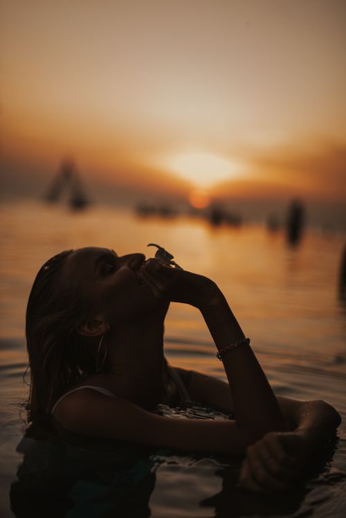 Free Artistic silhouette of a woman in ocean at sunset in Bali, Indonesia. Stock Photo