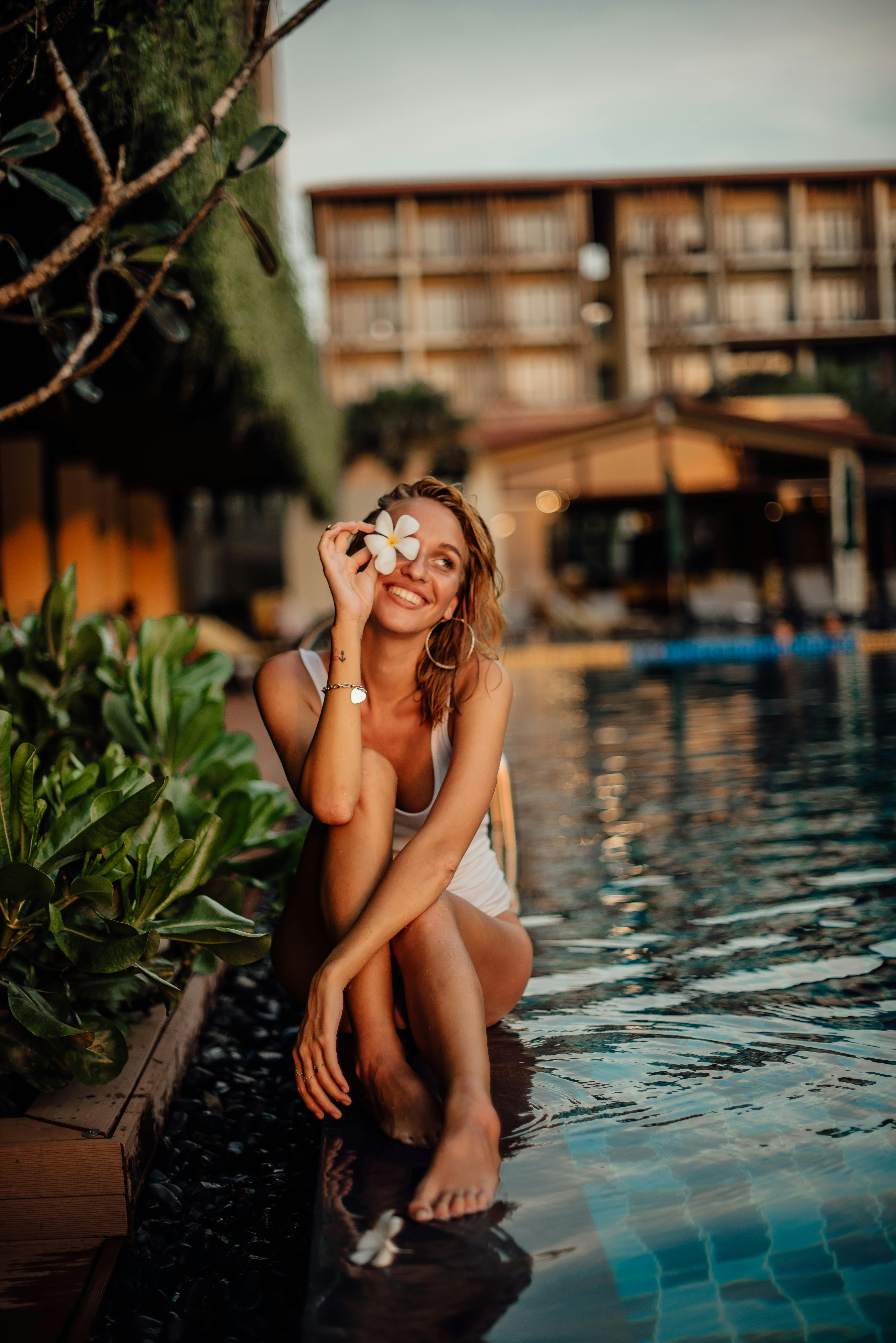 a woman sitting in the poolside holding a plumeria