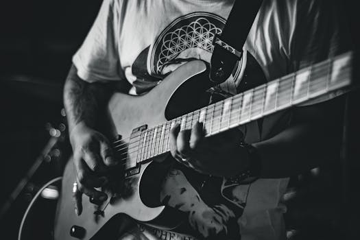 Monochrome image of a guitarist playing an electric guitar passionately indoors.