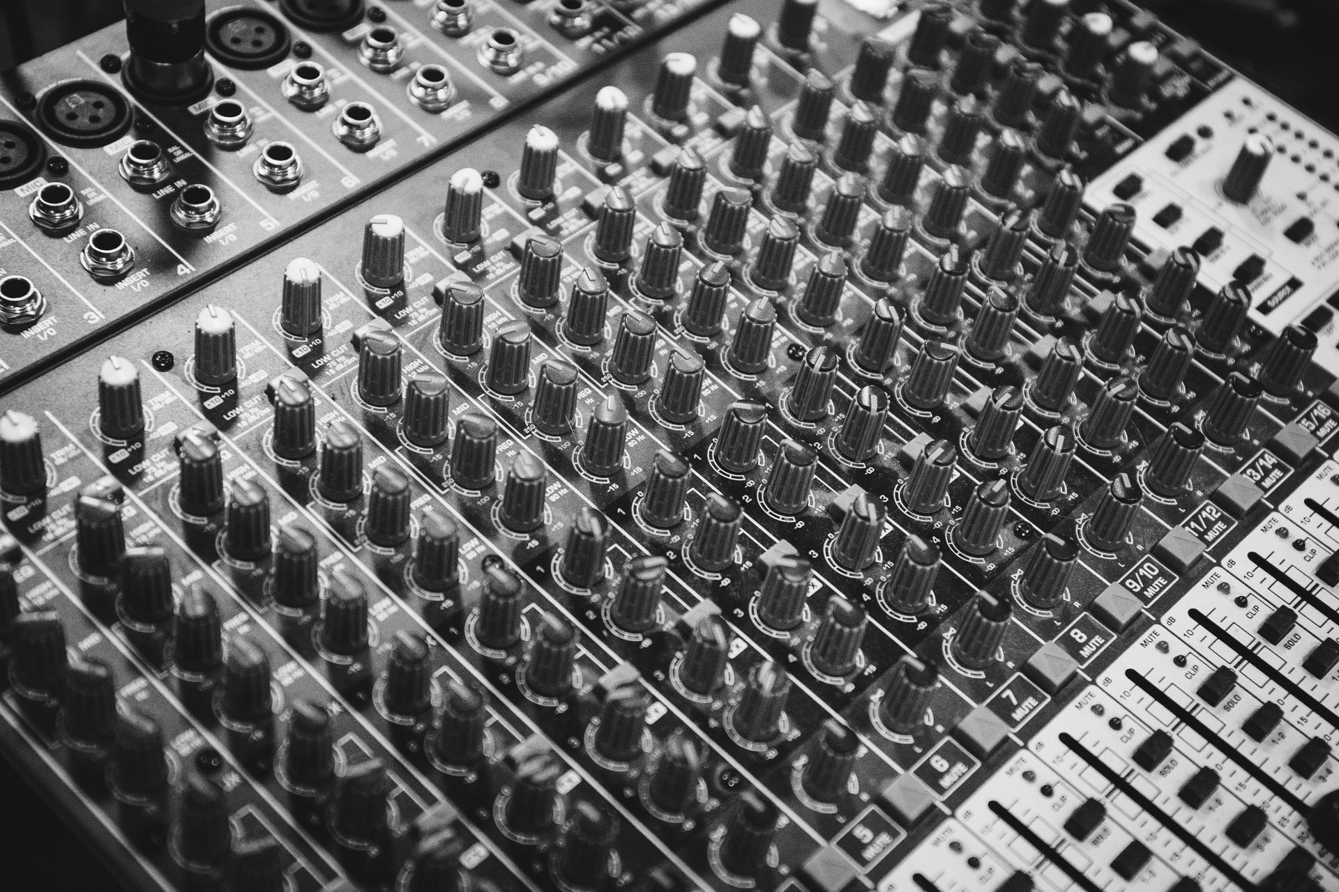 Detailed close-up of audio mixer knobs in monochrome, showcasing precision in musical equipment.
