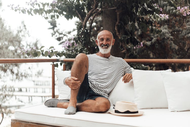 Happy Mature Ethnic Male Resting On Sofa On Terrace