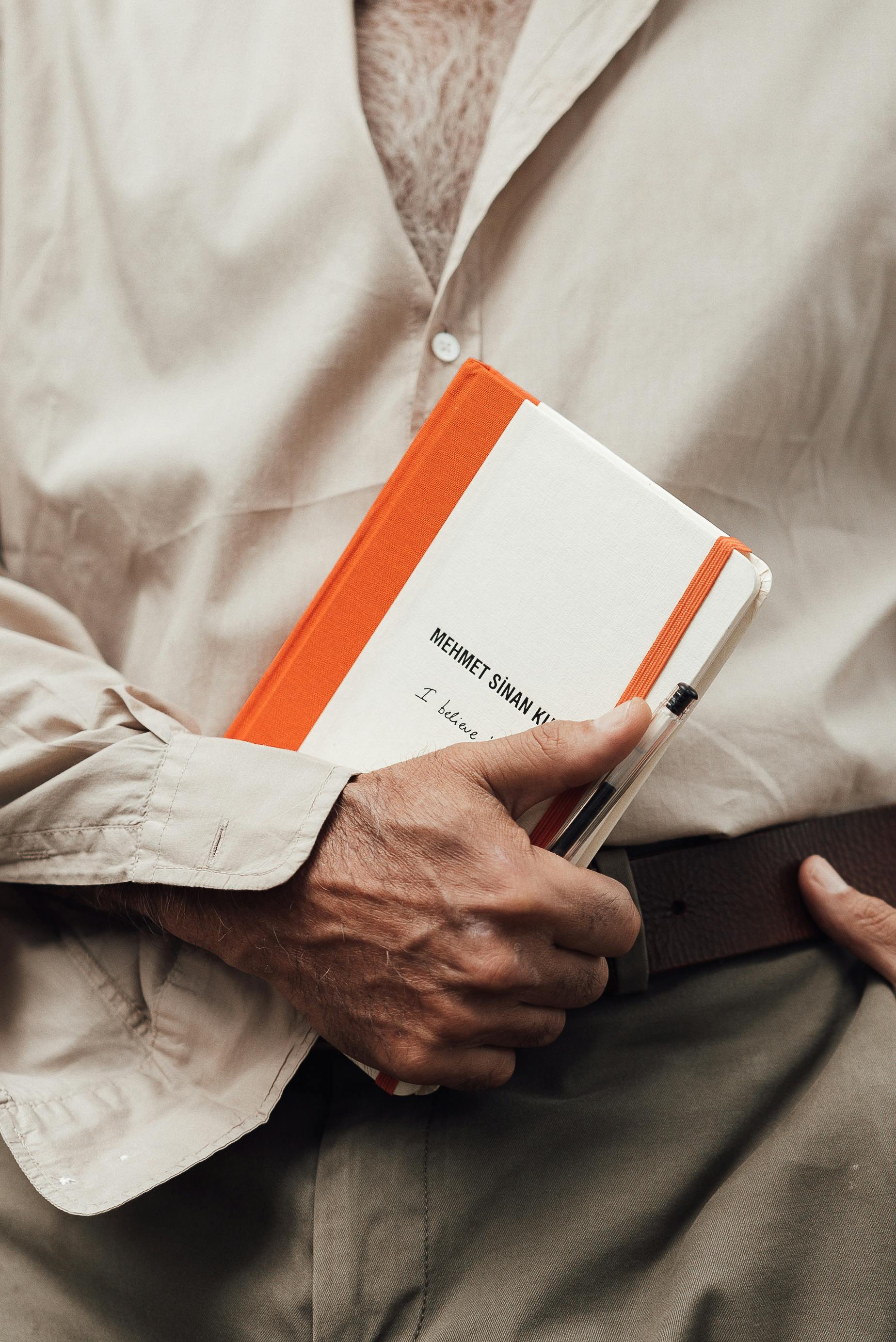 crop faceless man in unbuttoned shirt holding book