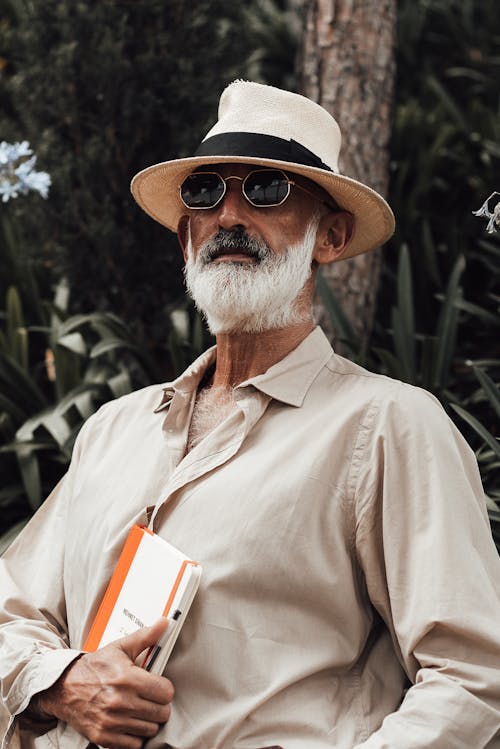 Stylish senior man with book standing in park