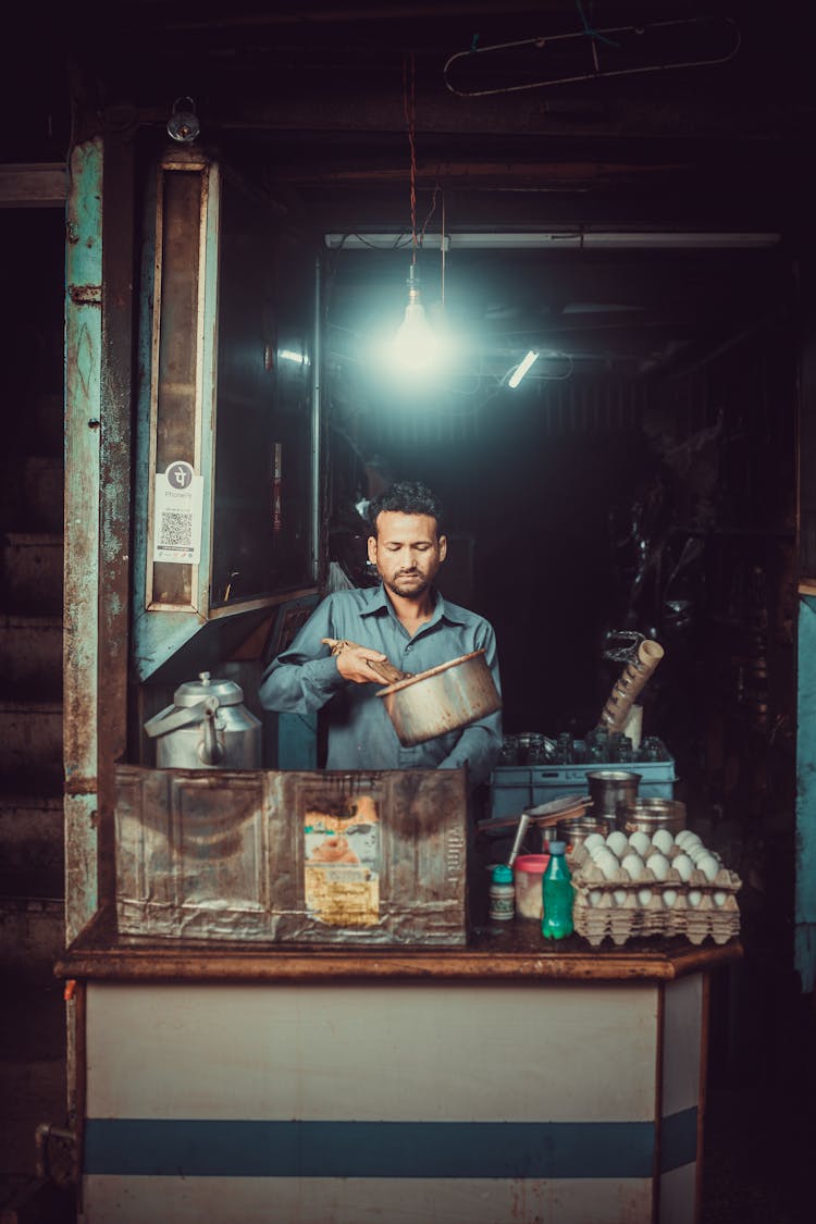  A Man In Blue Long Sleeves Cooking A Food