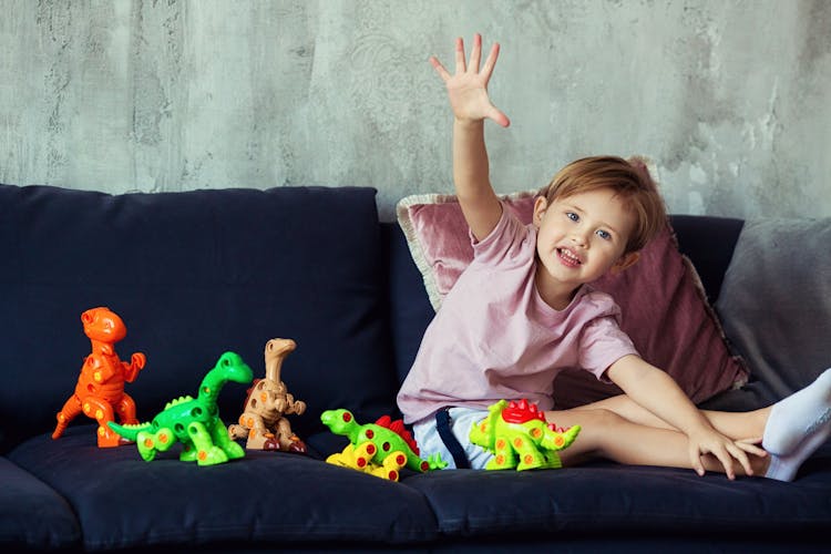 Girl Sitting On Blue Sofa Playing Dinosaur Toys