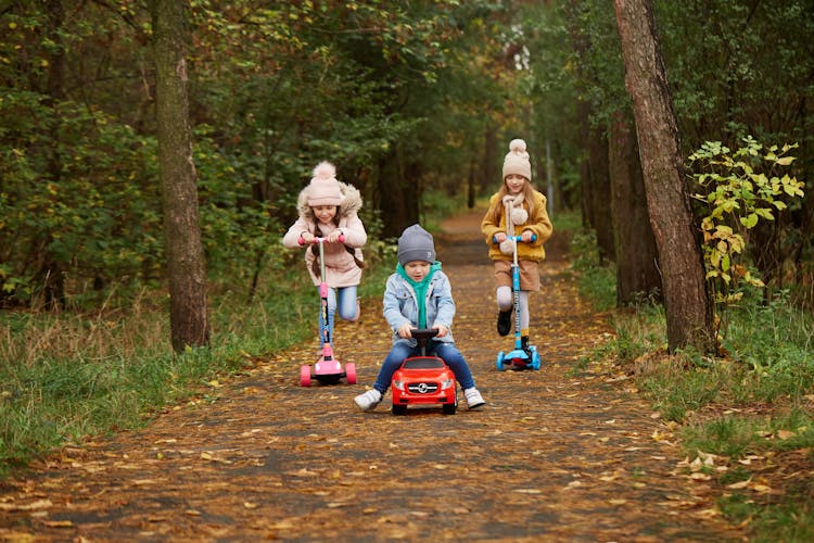 Kids Riding Toy Car And Trollies In A Forest Road