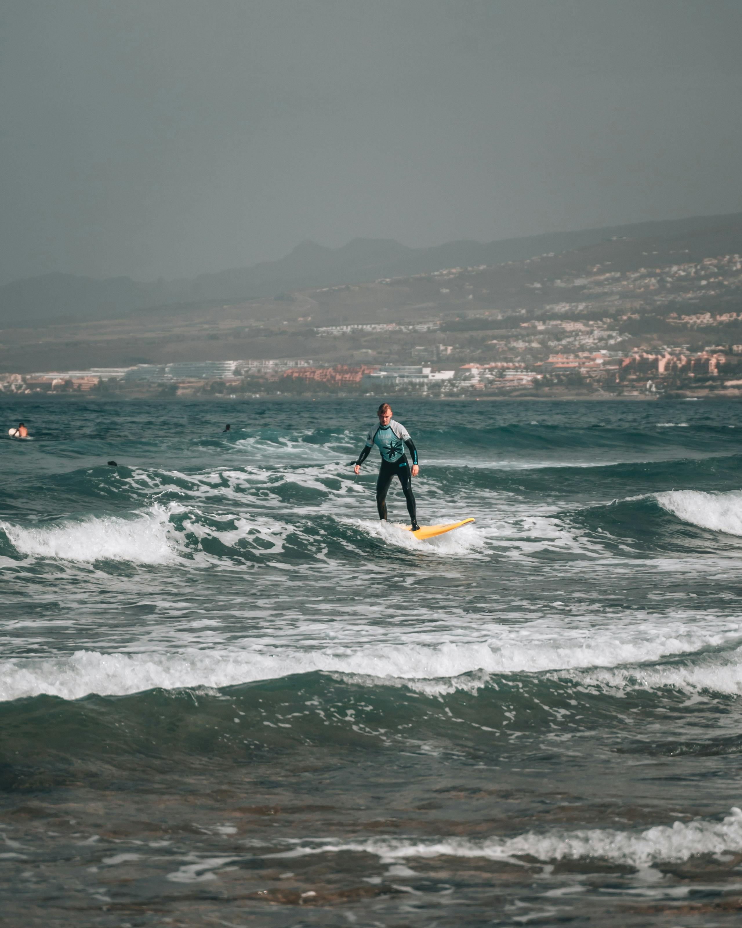 Surfer skillfully rides ocean waves in Santa Cruz de Tenerife's scenic seascape.