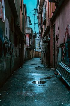 A wet, narrow alleyway in Gaziantep, Turkey, captured after a rain. The urban setting features graffiti and a cool atmosphere.