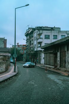 A quiet urban street in Gaziantep, Turkey, featuring buildings and a car on a cloudy day.