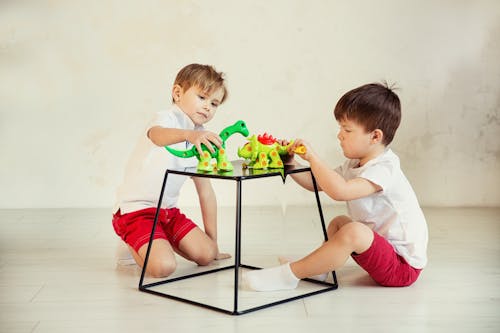 Kids Sitting on the Floor While Playing Dinosaur Toy