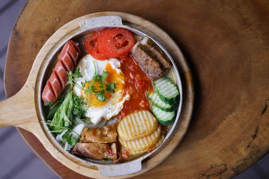 Delicious Vietnamese breakfast platter featuring eggs, sausage, and fresh vegetables on a wooden table.